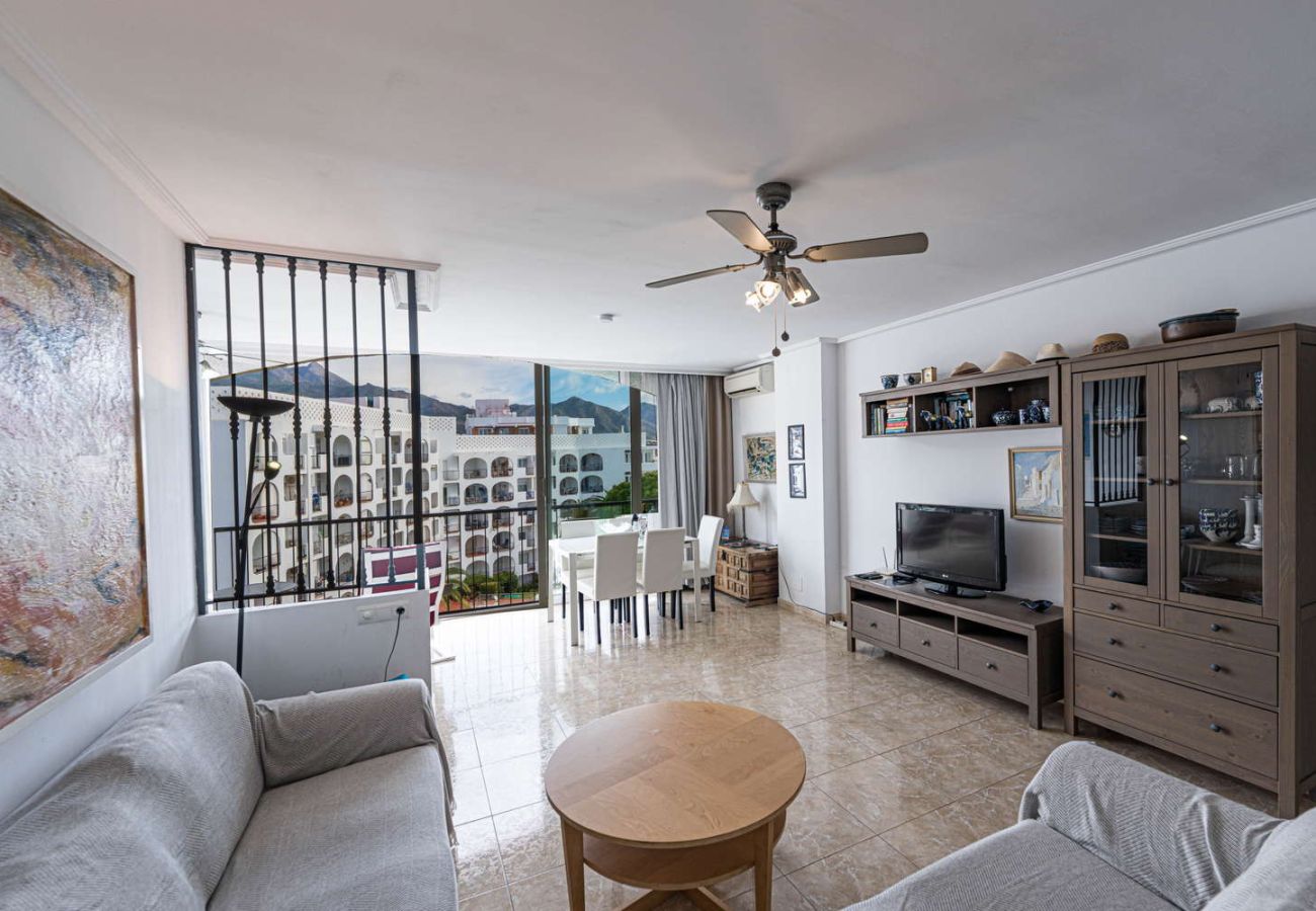 Salón luminoso con sofá y TV en apartamento de alquiler vacacional para 4 personas en Nerja