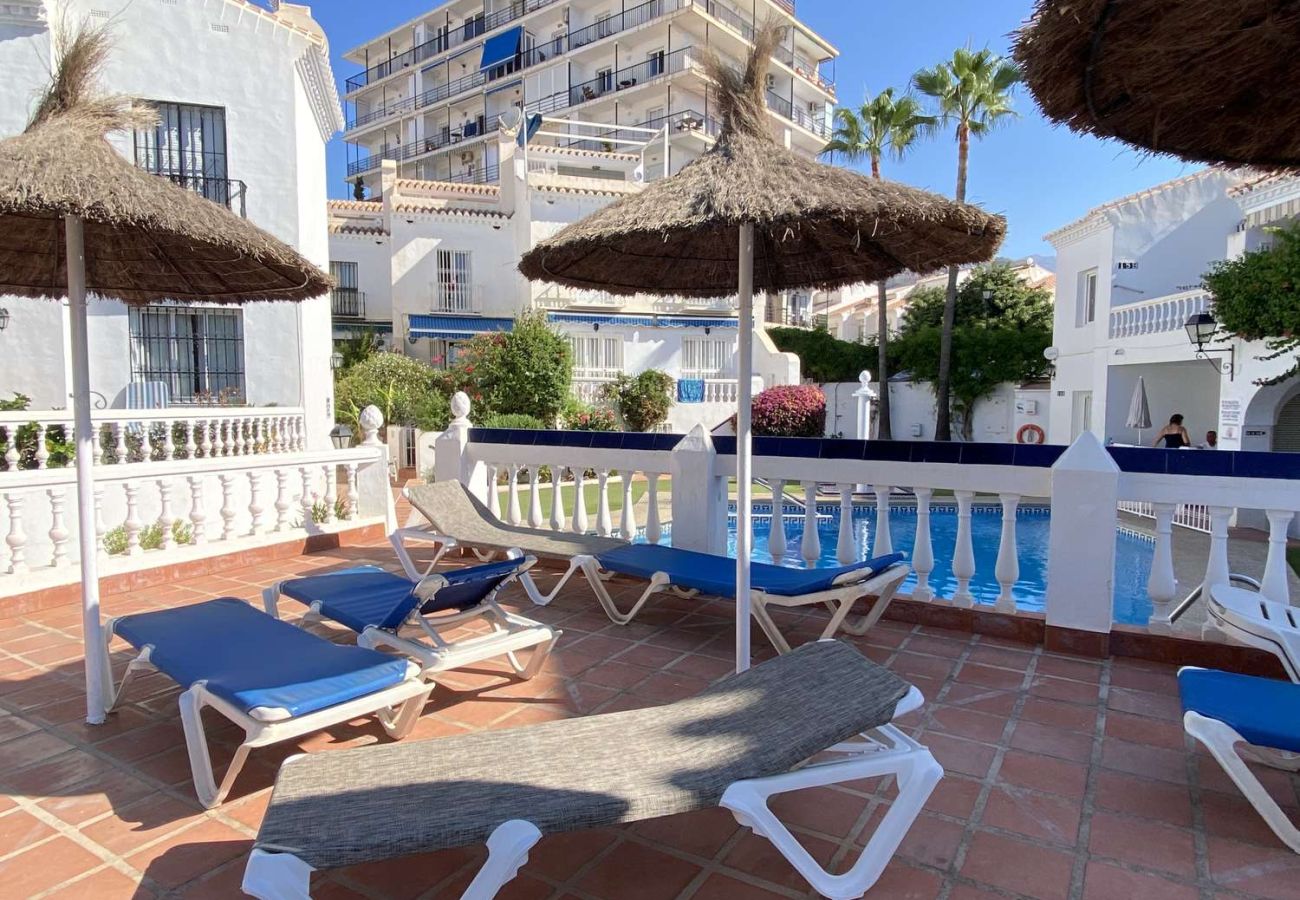 Zona de tumbonas y sombrillas junto a la piscina en complejo en Nerja