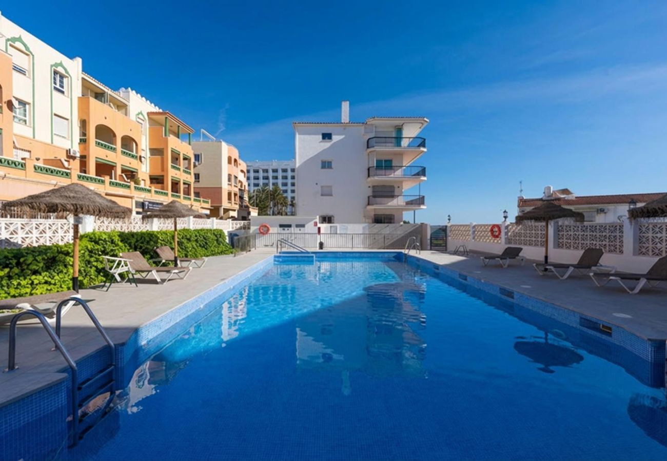 Piscina comunitaria del edificio Arce 5 con zona de sombrillas y tumbonas.