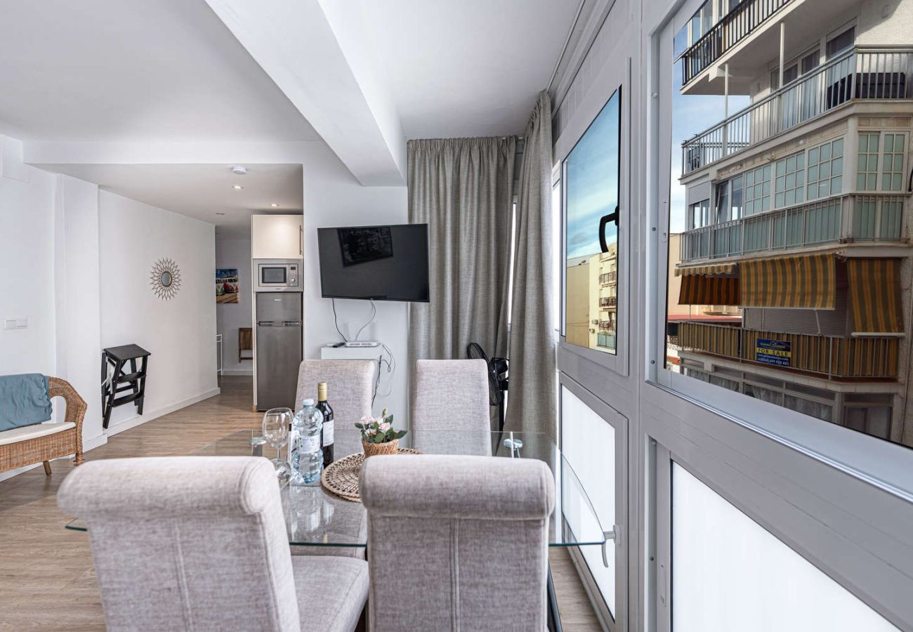 Zona de comedor con mesa de cristal junto a gran ventanal luminoso en Nerja.