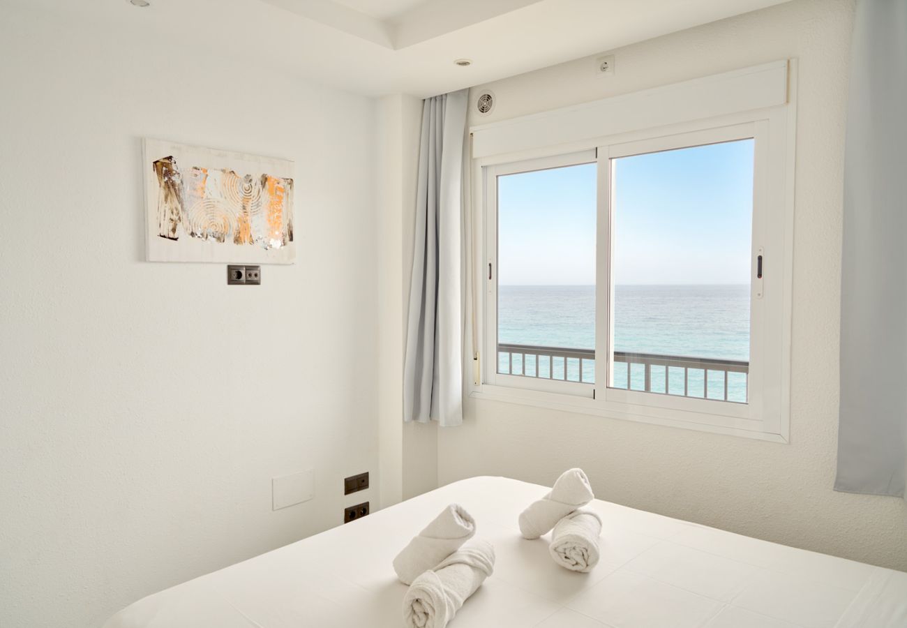 Dormitorio principal con cama doble y vistas frontales al mar desde la ventana en Nerja.