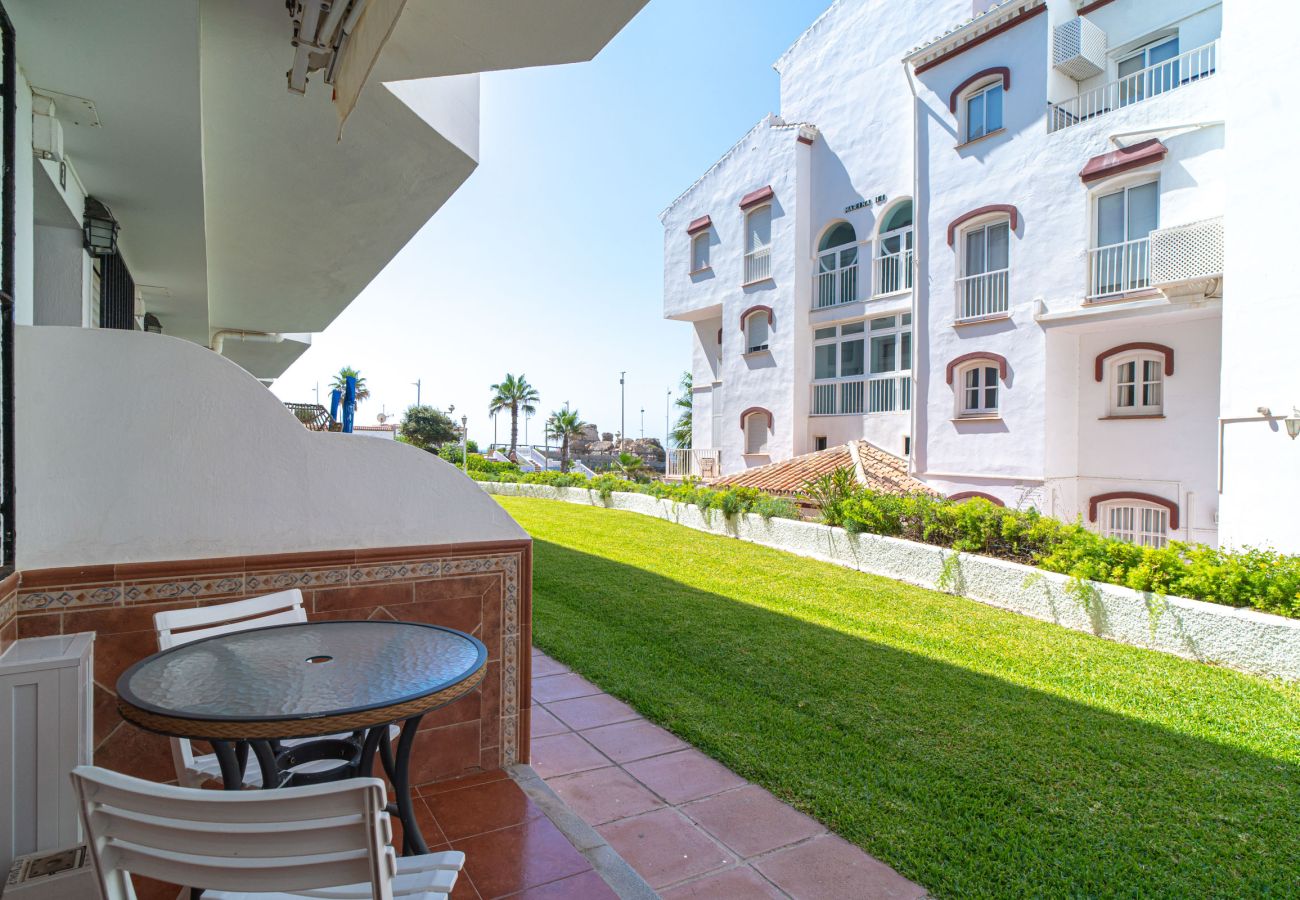 Terraza de entrada del apartamento Arce 2 con mesa y sillas frente al jardín comunitario.