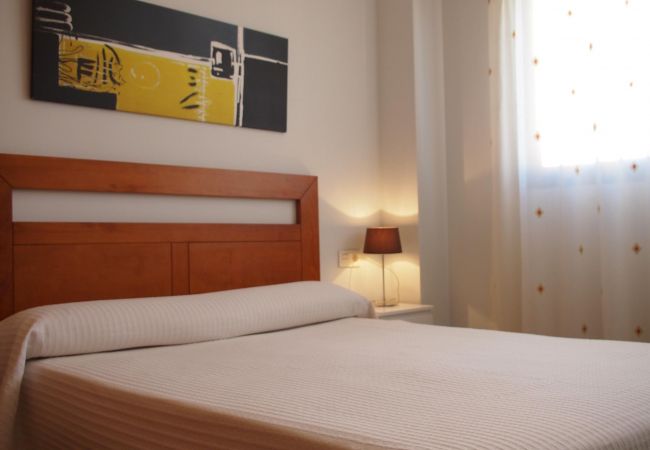 The master bedroom has a double bed, a bedside table with a lamp and it is bright and airy.