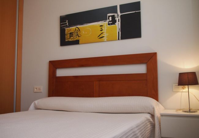 The master bedroom has a double bed, a bedside table with a lamp and it is bright and airy.