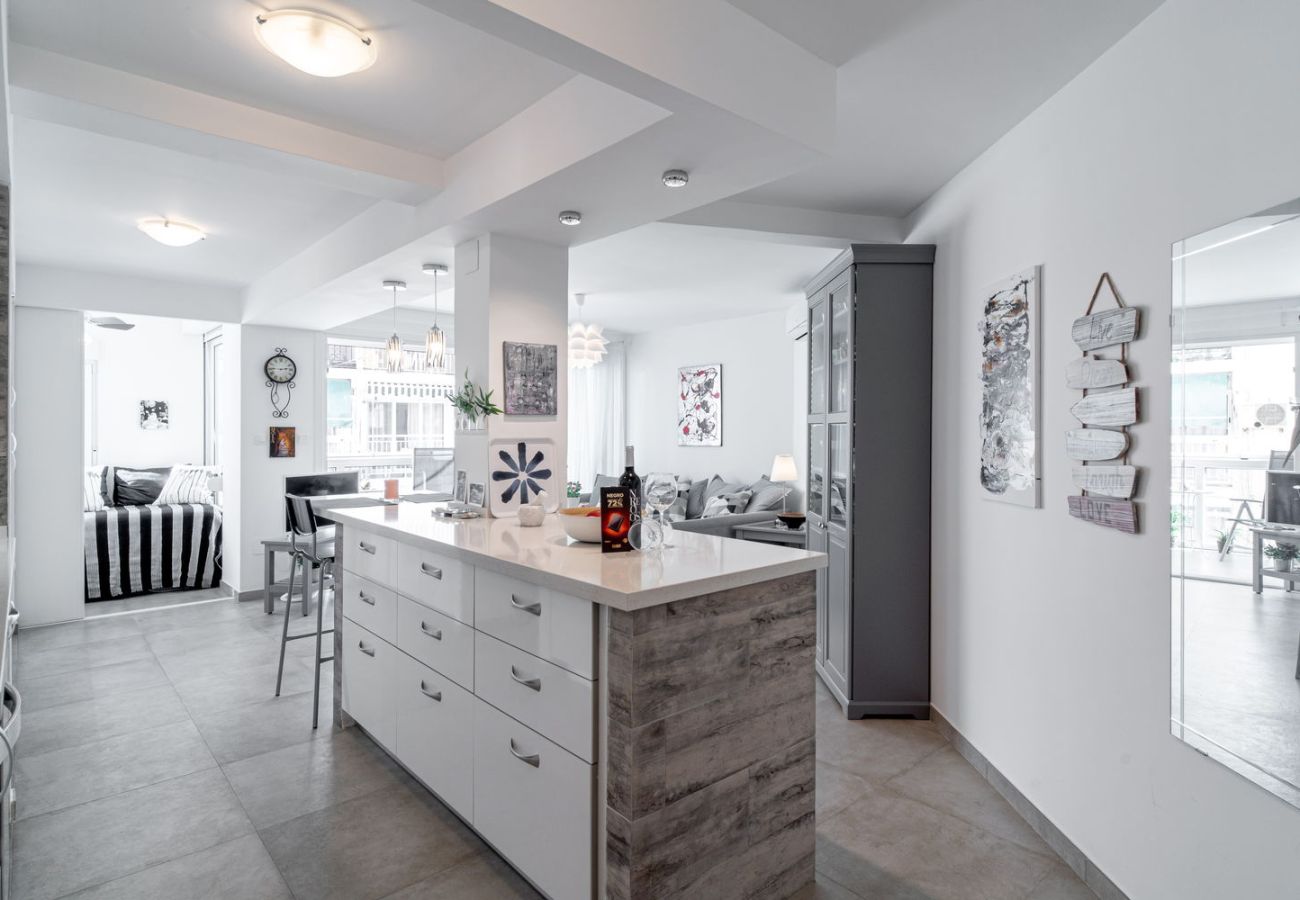 Dining area with wooden table and designer chairs next to the equipped kitchen in Nerja.